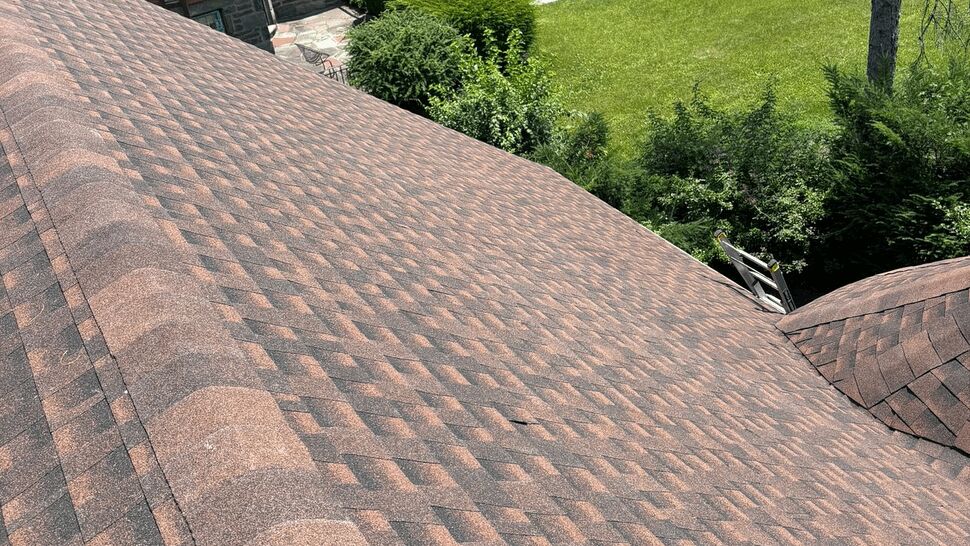 Aerial view of brown asphalt shingle roof and landscaped yard.