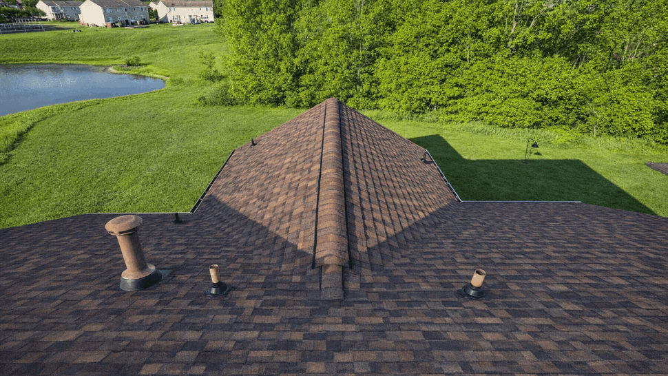 Roof Vent Stacks and Ridge | Tycos Roofing And Siding Inc Roof with multiple vent stacks and ridge vent near pond and trees