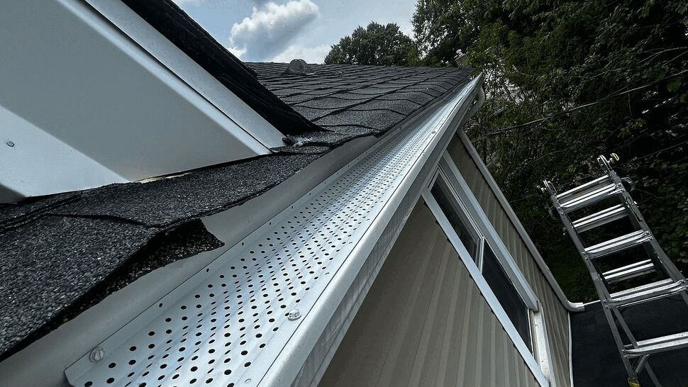 Aluminum Gutter Guard Installation | Tycos Roofing And Siding Inc Close-up of perforated aluminum gutter guard along shingled roof edge