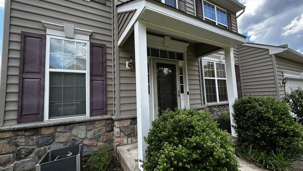 Angled view of porch showing vinyl siding, stone veneer and decorative shutters.