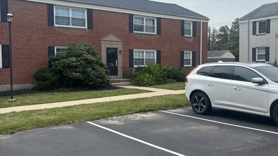 Brick two-story apartment building with parking and visible roofline.