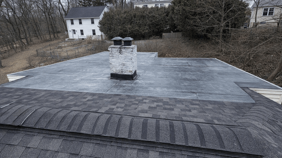 Flat Roof Membrane with Chimney | Tycos Roofing And Siding Inc Flat roof membrane area with chimney and surrounding shingles.