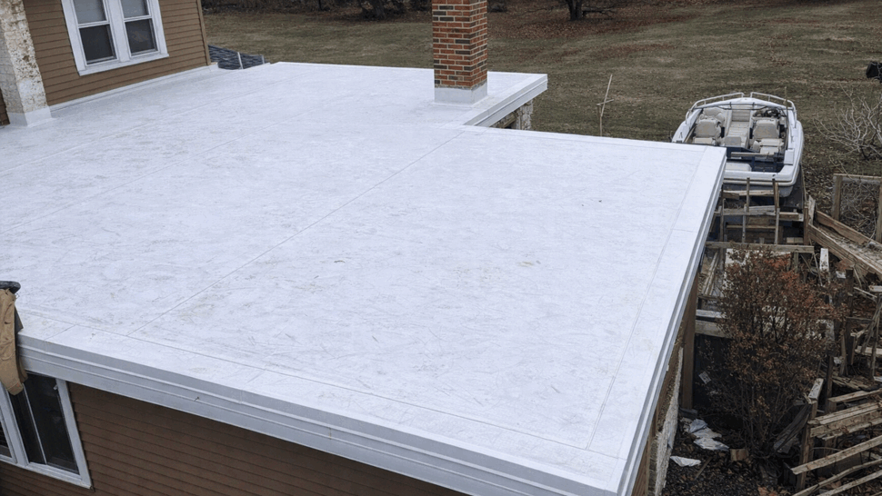 Flat Roof Membrane Installation | Tycos Roofing And Siding Inc White single-ply flat roof membrane viewed from above with roof edge and gutter