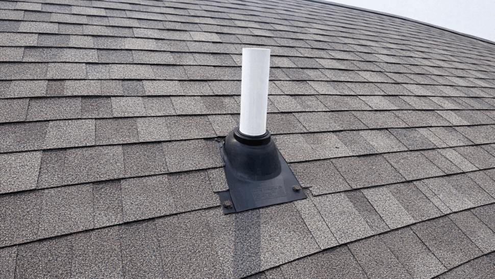 Close-up of a roof vent pipe with rubber flashing on shingles