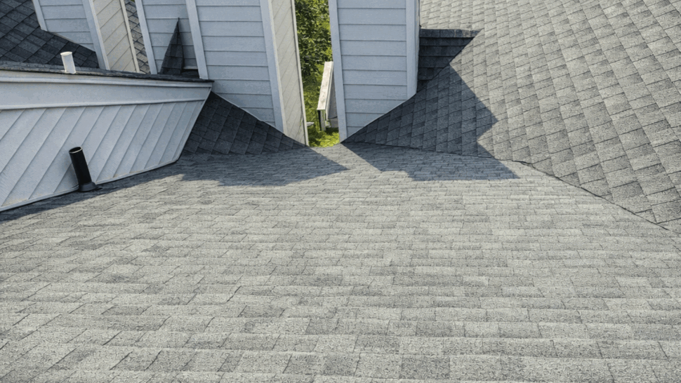 Asphalt shingle roof with four white chimneys and a center roof valley