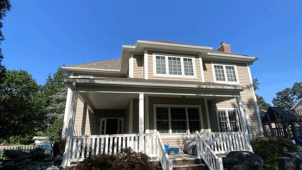 Rear porch and deck area with stairs, outdoor furniture, and landscaping.