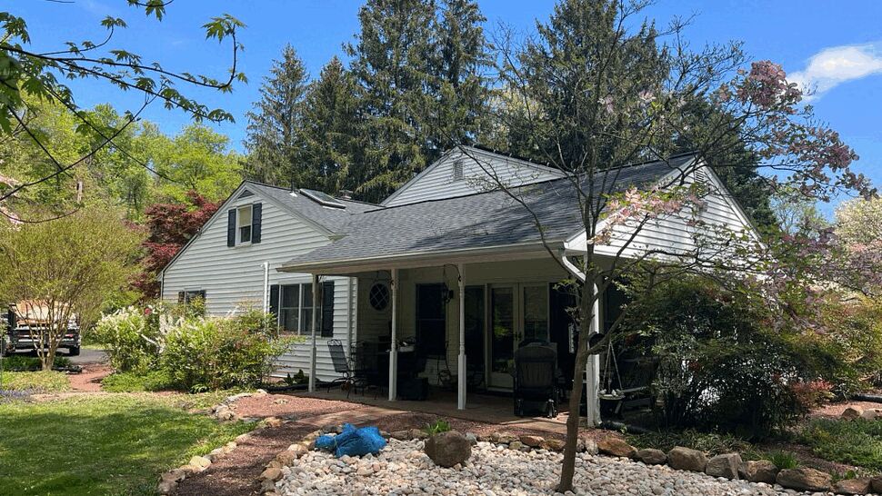 Backyard covered porch with seating, rock garden and mature trees