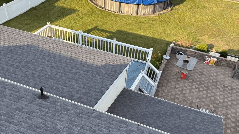 Backyard with above-ground pool, deck, patio and fenced yard viewed from above.