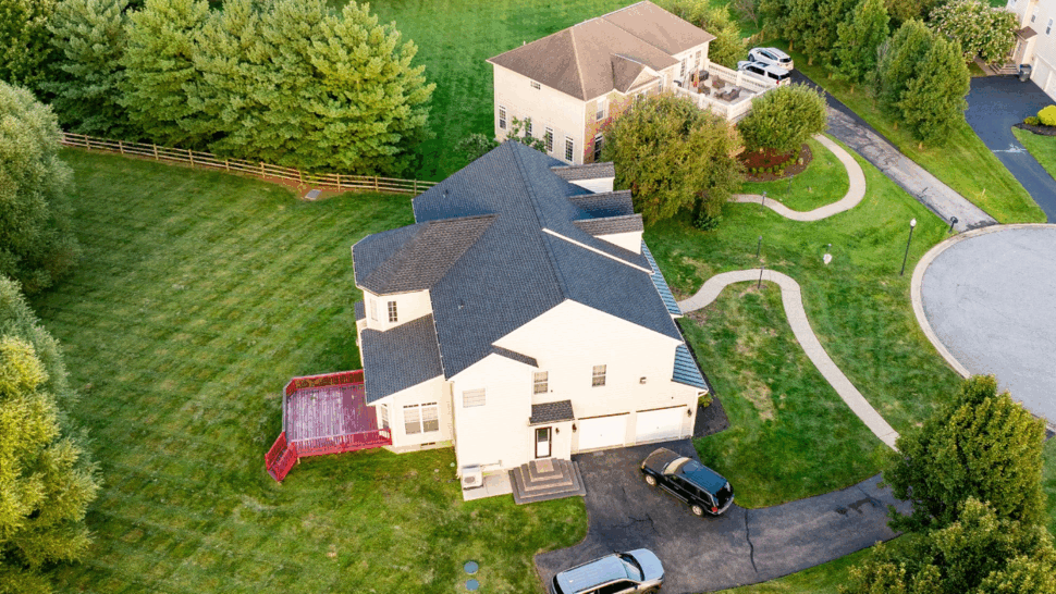 Backyard view with red deck and shingled roof from above