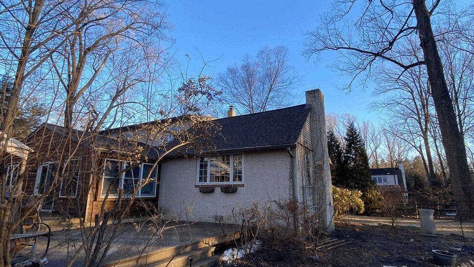 Backyard view with wooden deck, stone path and adjacent roofline