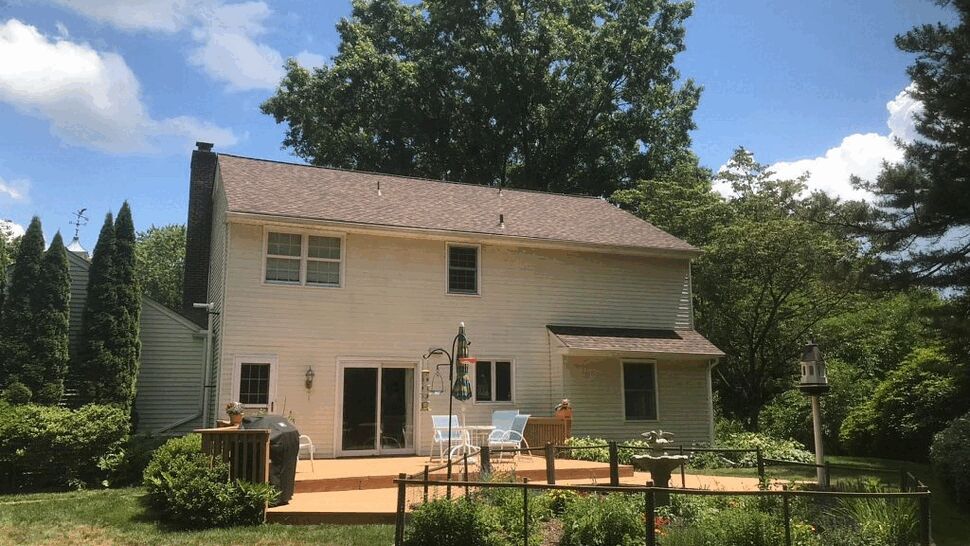 Rear view of house with deck, sliding doors and asphalt shingle roof.