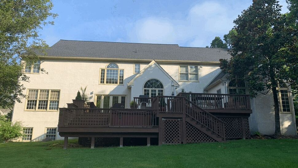 Rear view of house featuring a large multi-level wooden deck and well-kept lawn.