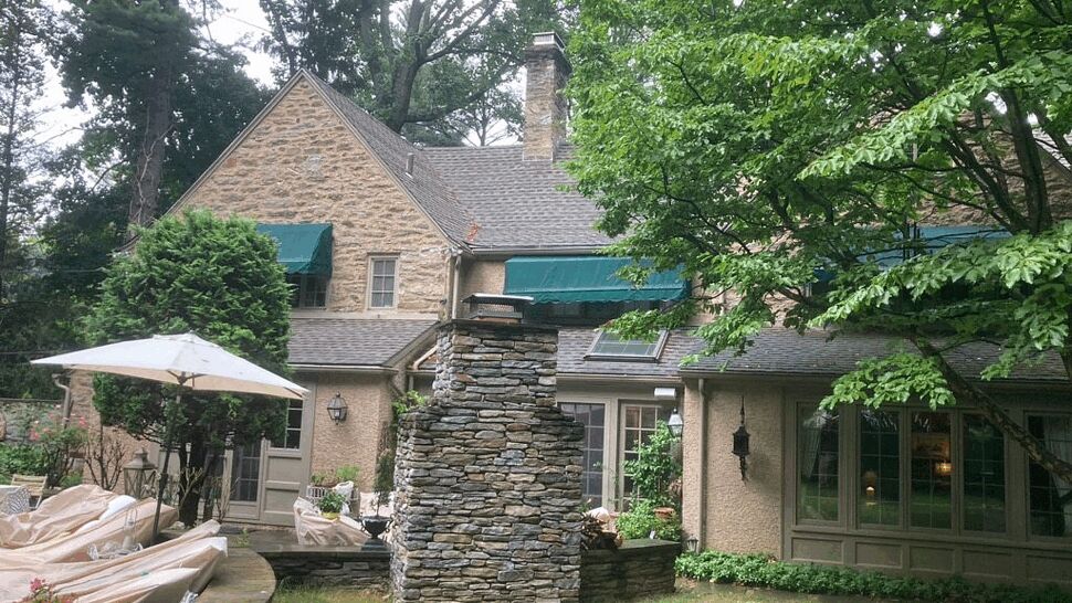 Backyard patio with stone chimney and green window awnings