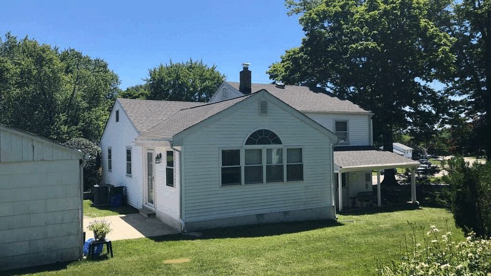 Backyard view of house with vinyl siding and arched window