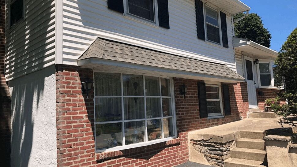 Close-up of bay window with brick base and shingled awning