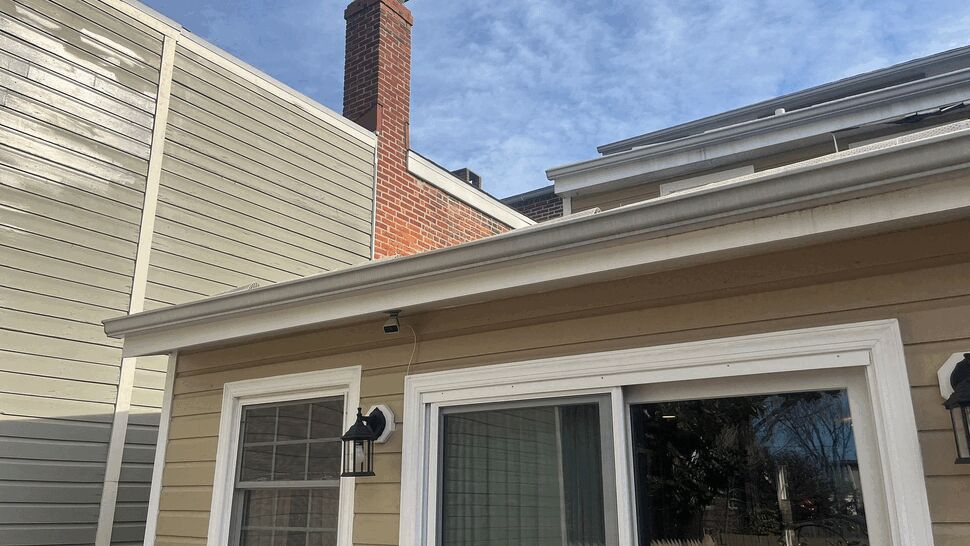 Beige siding with white trim and sliding glass door under a gutter.