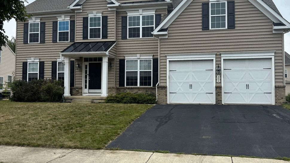 Two-story beige house with siding, black shutters, front door and double garage.