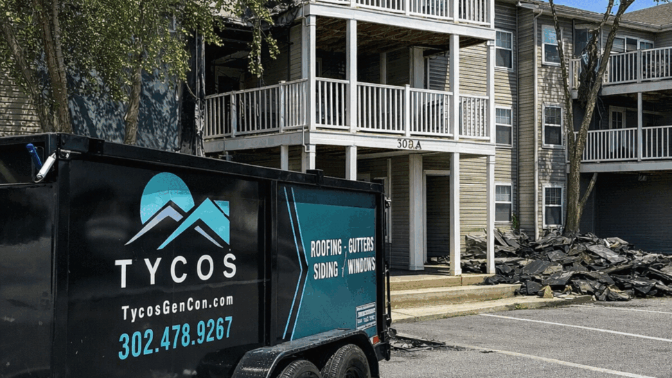 Tycos trailer and roofing debris piled outside a multi-unit apartment