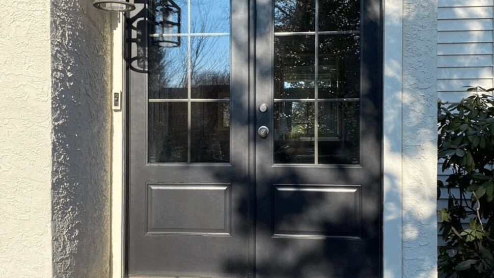Black double exterior doors with glass panes and wall lantern.