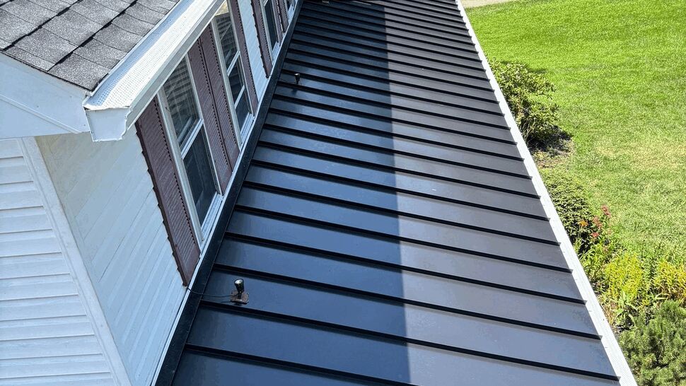 Close-up of black standing seam metal roof panels and gutter