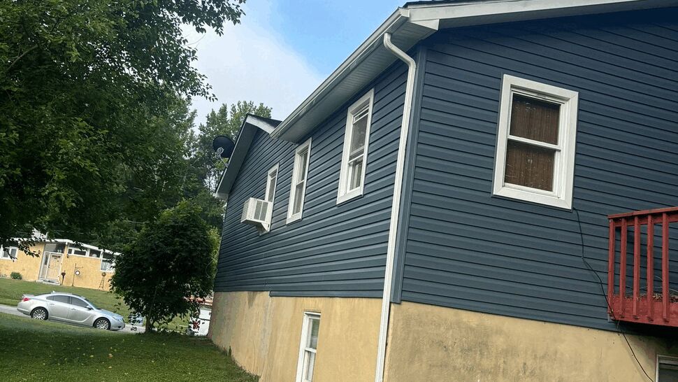 Side view of house with blue siding and white gutter downspout