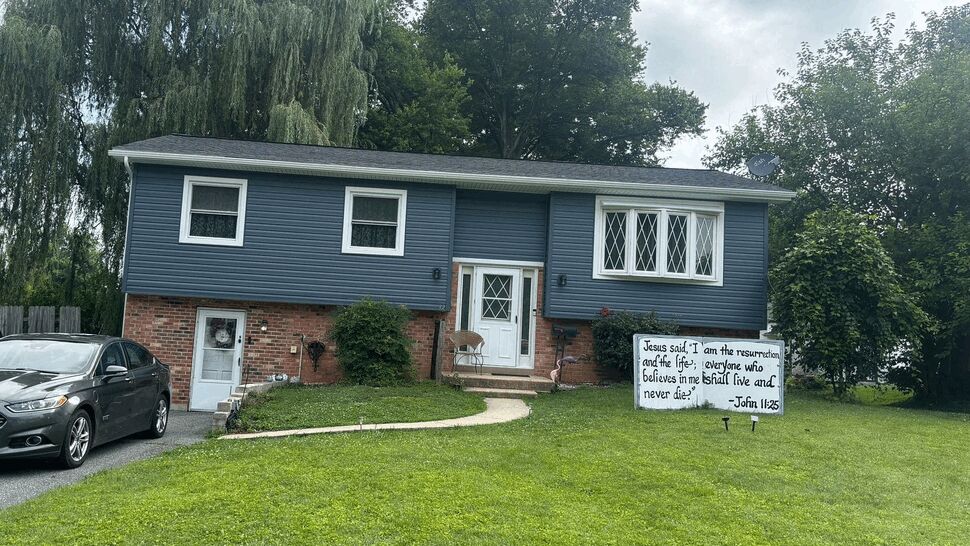 Split-level home with blue siding, brick base, white door and front lawn