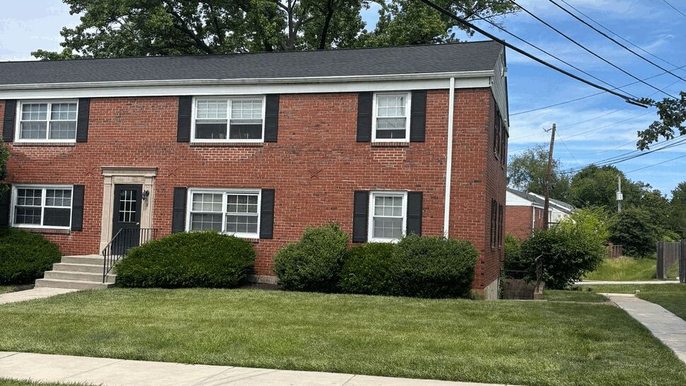 Brick apartment building front with new shingle roof and white gutters