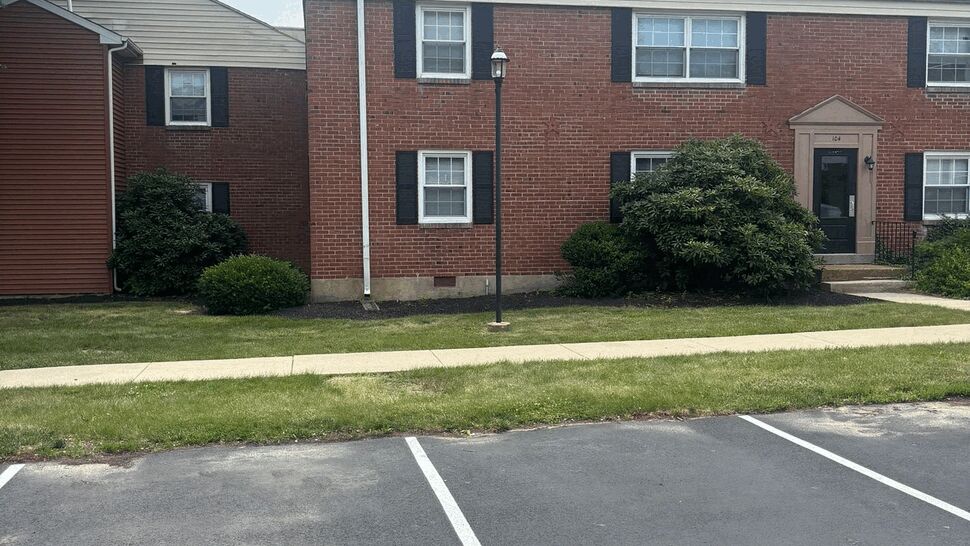 Brick building facade with a downspout and lamp post near the sidewalk.