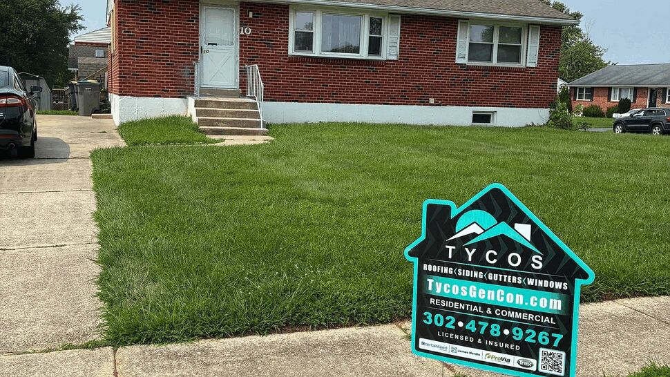Brick bungalow with Tycos yard sign on front lawn and visible asphalt roof
