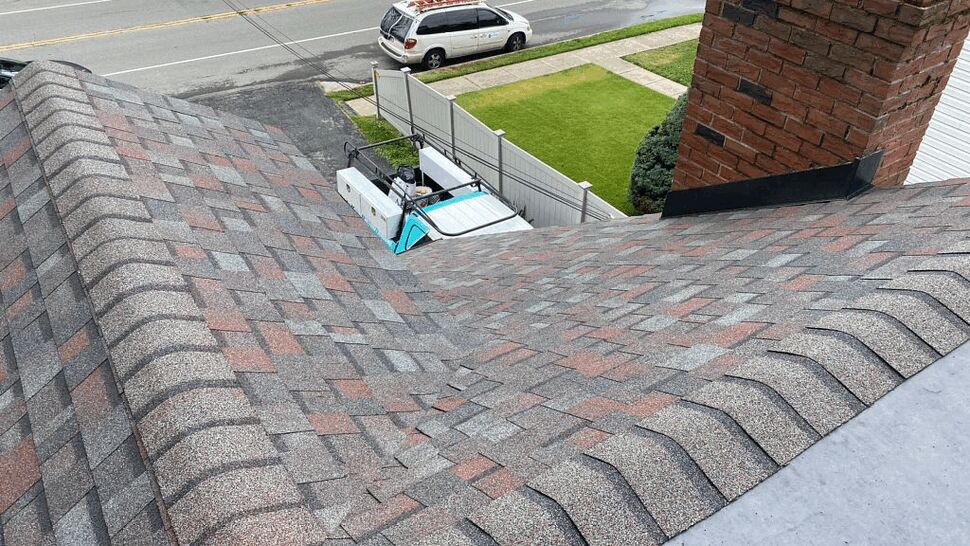 Roof valley and chimney flashing with patterned shingles and work truck below