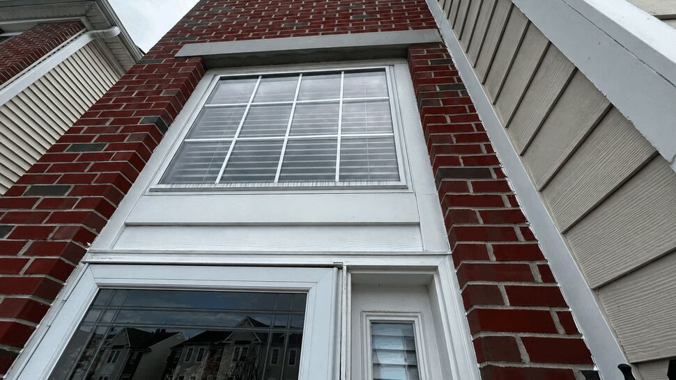 Brick Column and Vinyl Siding Detail | Tycos Roofing And Siding Inc Upward view of brick column and adjacent vinyl siding around windows