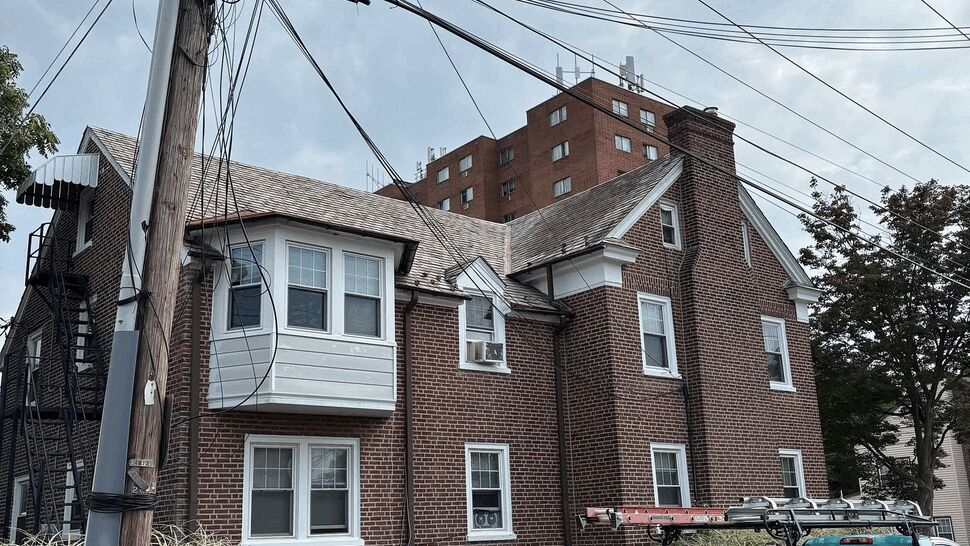 On-site at brick multi-family home | Tycos Roofing And Siding Inc Brick multi-family home with Tycos Roofing And Siding Inc service truck parked outside