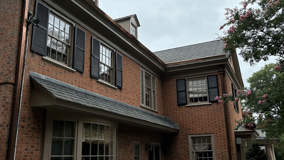 Side view of brick house with bay window, black shutters and landscaped pathway