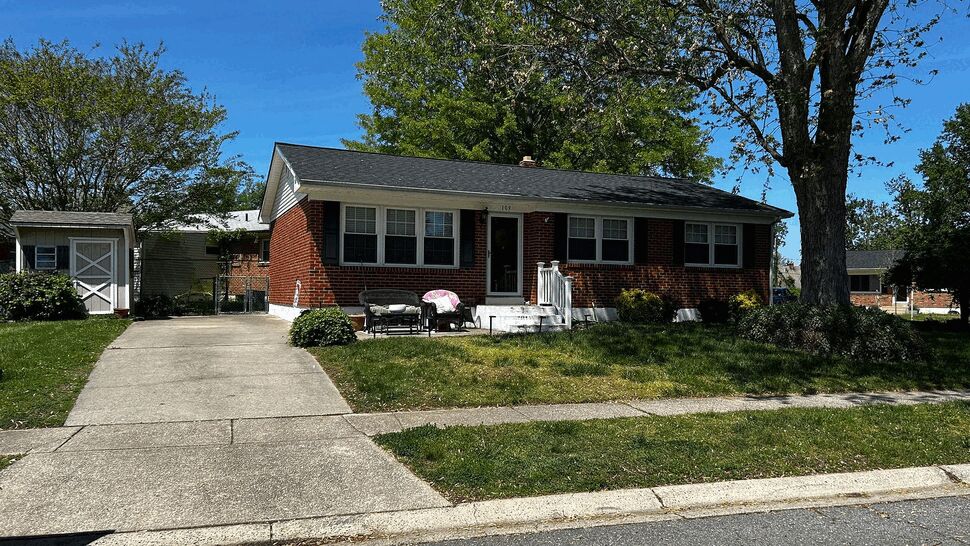 Front view of brick ranch house with driveway and shingled roof.
