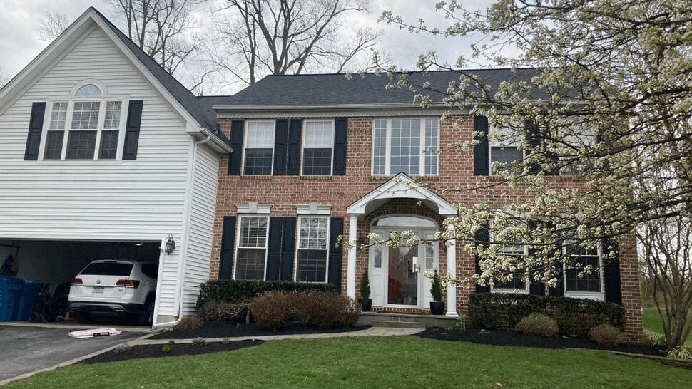 Two-story brick and siding house with dark shingle roof and front lawn