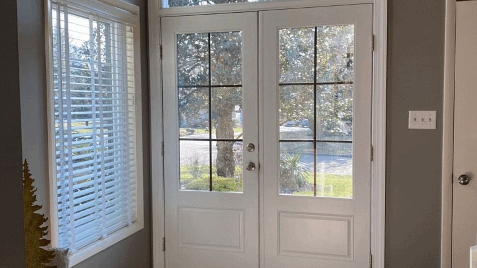 Interior view of white glass-paneled double doors with transom window.