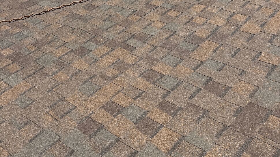 Brown asphalt shingle roof with deck edge and gutter visible