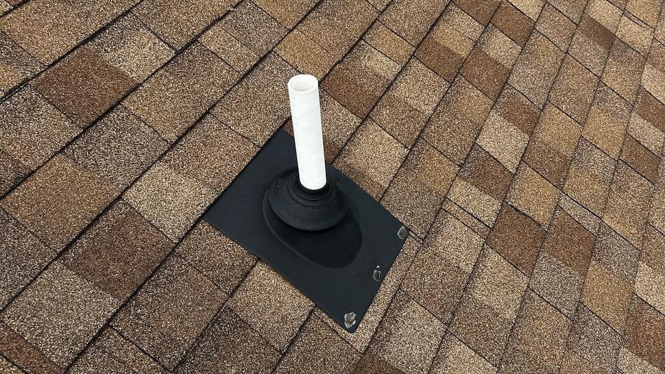 Asphalt shingle roof with white vent pipe and black flashing