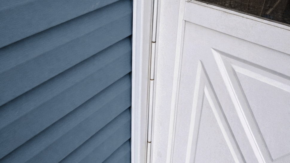 White Entry Door and Siding | Tycos Roofing And Siding Inc White entry door beside blue horizontal siding and white trim.