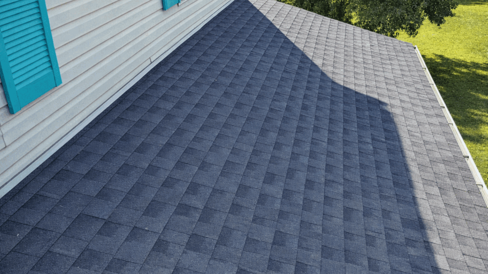 Asphalt shingle roof with white gutter and teal shutters beside a window