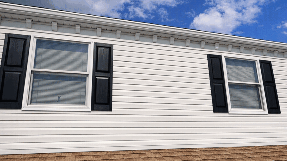 Shingle roof with second-floor windows and black shutters under blue sky