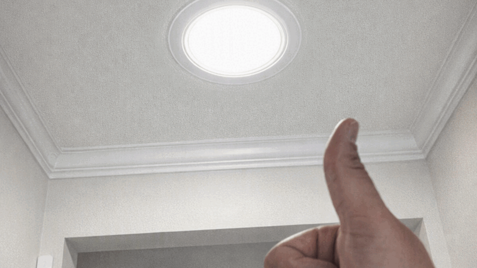 Bright round tubular skylight light in an interior ceiling with a thumbs-up
