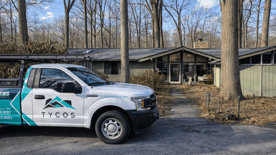Service truck at residential roofing job | Tycos Roofing And Siding Inc Tycos pickup truck parked in front of a midcentury house at a roofing job site.