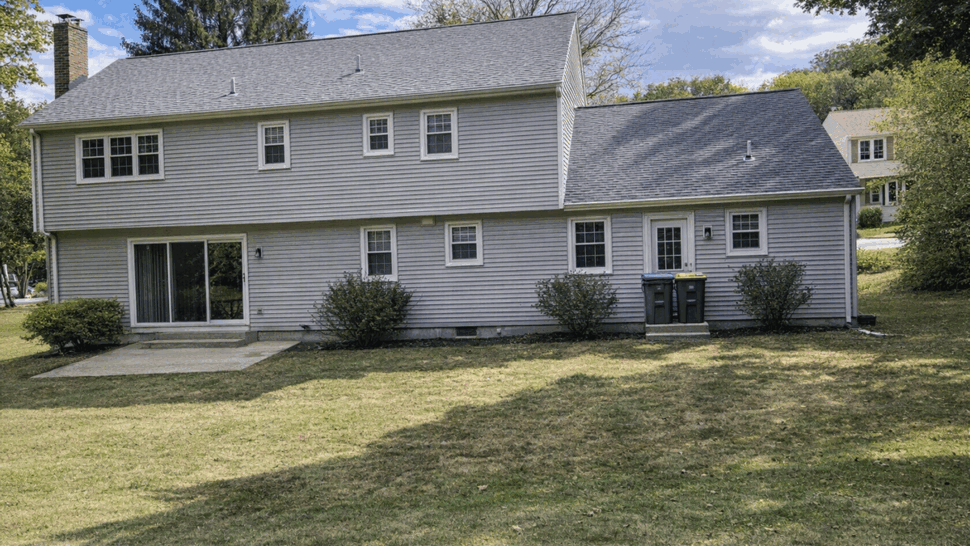 Rear elevation of house with new dark shingles and sliding glass door
