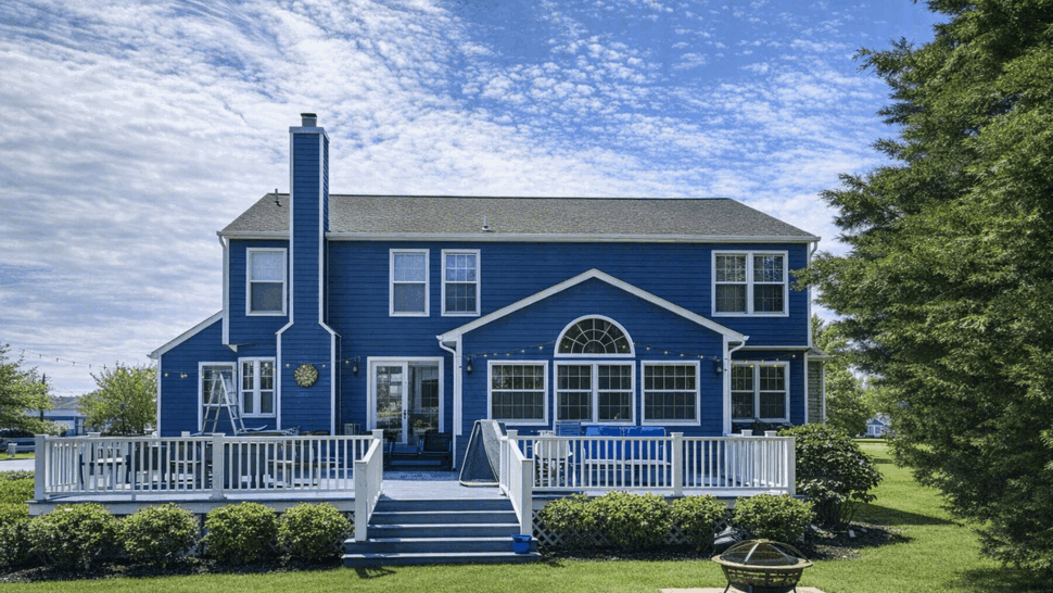 Spacious Backyard Deck Installation | Tycos Roofing And Siding Inc Backyard view of a blue house with a large white deck and patio area.