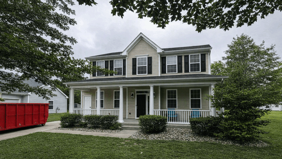 Two-Story Front Siding and Porch | Tycos Roofing And Siding Inc Front view of a two-story beige house with covered porch and landscaped lawn