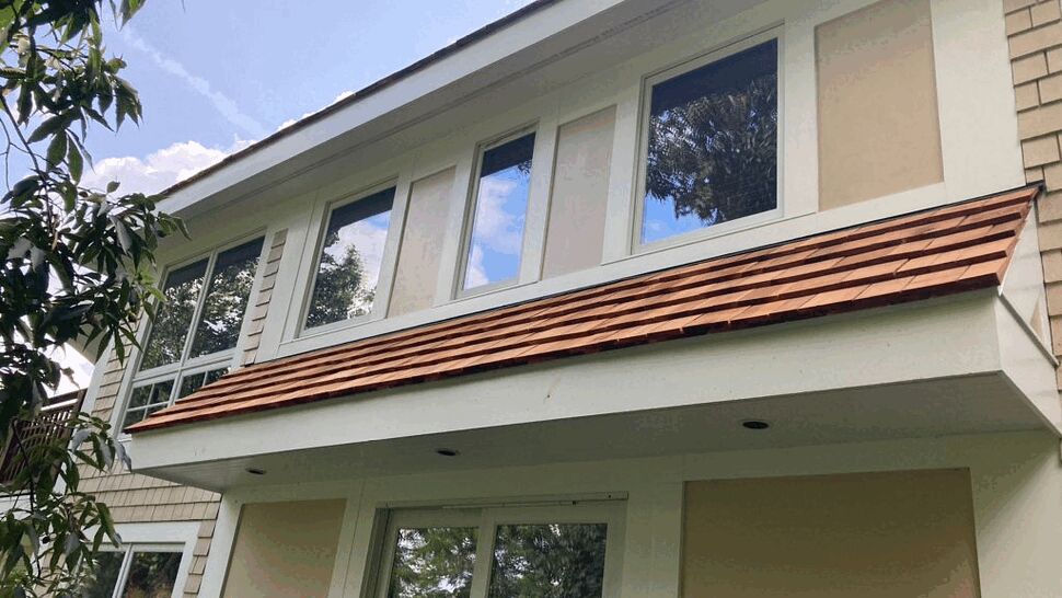 Exterior view of second-story windows with cedar shingle awning