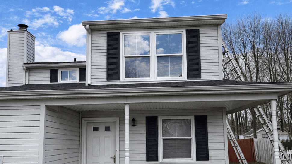 Front Porch Siding and Windows | Tycos Roofing And Siding Inc Gray-sided home facade with front porch, windows, shutters, and gutters.