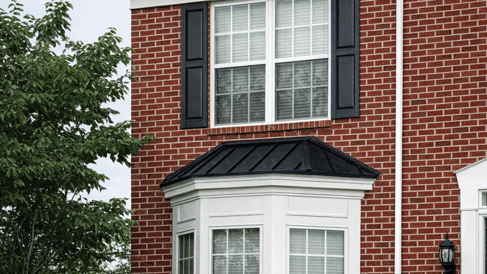 Bay window with white trim and a black standing-seam metal roof below a double-hung window.