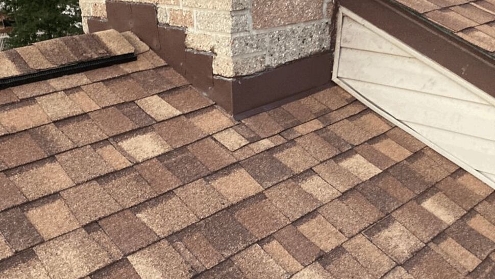 Chimney base with metal flashing integrated into surrounding shingles